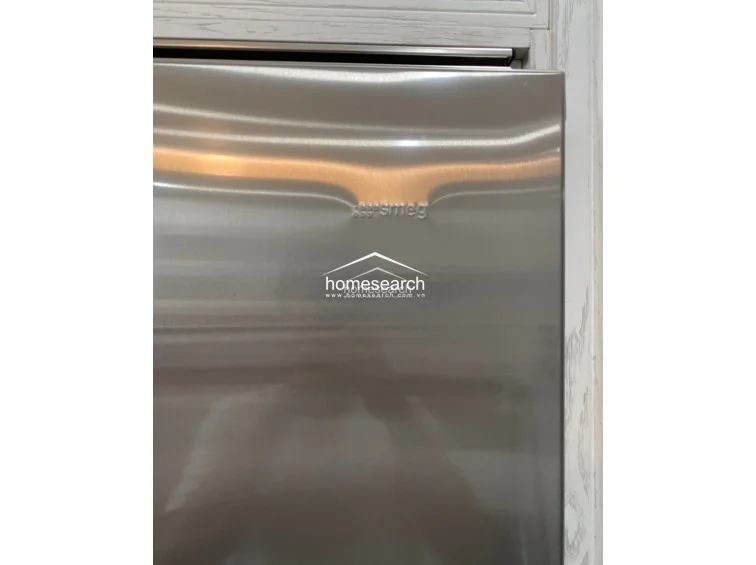 This image features a high-end Smeg stainless steel appliance integrated into a kitchen cabinetry unit with a white, wood-grain finish. The appliance appears to be in excellent condition, reflecting a modern and luxurious kitchen aesthetic.