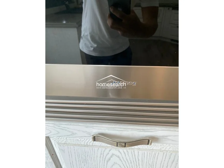 This close-up shows a high-quality Smeg appliance integrated into white, wood-textured cabinetry with ornate, vintage-style metal handles. The overall design suggests a high level of maintenance and a commitment to premium, stylish kitchen finishes.