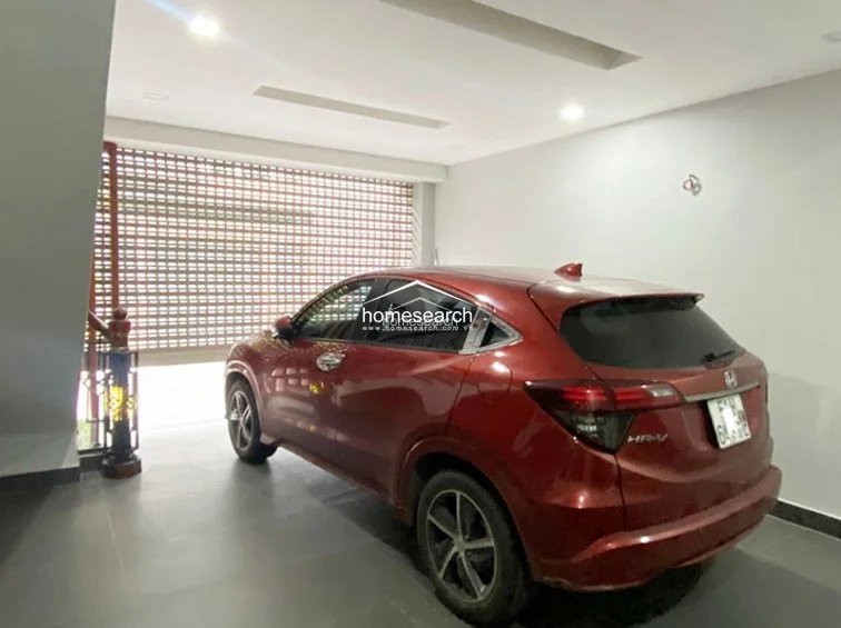 This interior garage space is finished with clean, neutral-toned walls and a smooth floor, providing a secure area for vehicle storage. The space is well-lit with recessed ceiling lights and includes a decorative staircase railing that suggests a high-quality interior design throughout the home.