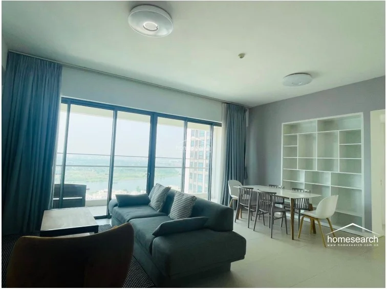 From this angle, the living space highlights a large built-in white shelving unit that provides ample storage and display space. The layout remains airy and cohesive, connecting the dining area to the rest of the open-plan living room. The combination of clean lines, modern ceiling-mounted lighting, and the expansive view creates a sophisticated and well-maintained atmosphere.