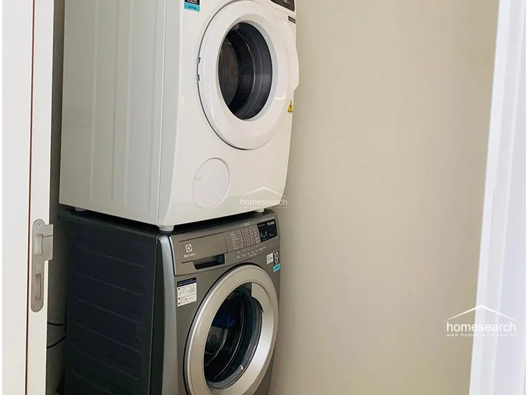 This dedicated laundry area is efficiently designed with a stacked washer and dryer unit, maximizing vertical space. The area is finished in neutral tones, keeping the utility space clean and unobtrusive.