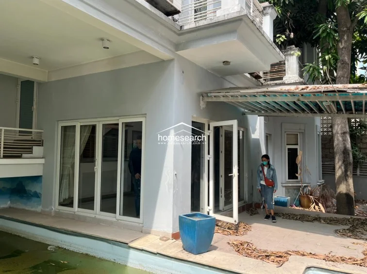 This image captures the rear outdoor space, featuring a private swimming pool that is currently in a state of neglect and requires professional cleaning. The area connects directly to the interior through large glass sliding doors, offering potential for a seamless indoor-outdoor flow once the pool and terrace are restored.