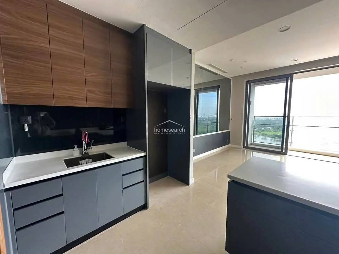 This view highlights the kitchen's efficient flow, showing the transition from the main cooking area to the open-concept living space. The sleek, minimalist aesthetic is maintained through handle-less cabinetry and a cohesive color palette of grey, white, and natural wood, reflecting a high level of contemporary maintenance.