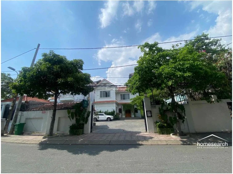 This perspective highlights the front facade of the villa, emphasizing the spacious paved courtyard suitable for multiple vehicles. The architectural style includes traditional roof tiles and large windows, suggesting a well-maintained, classic residential structure.