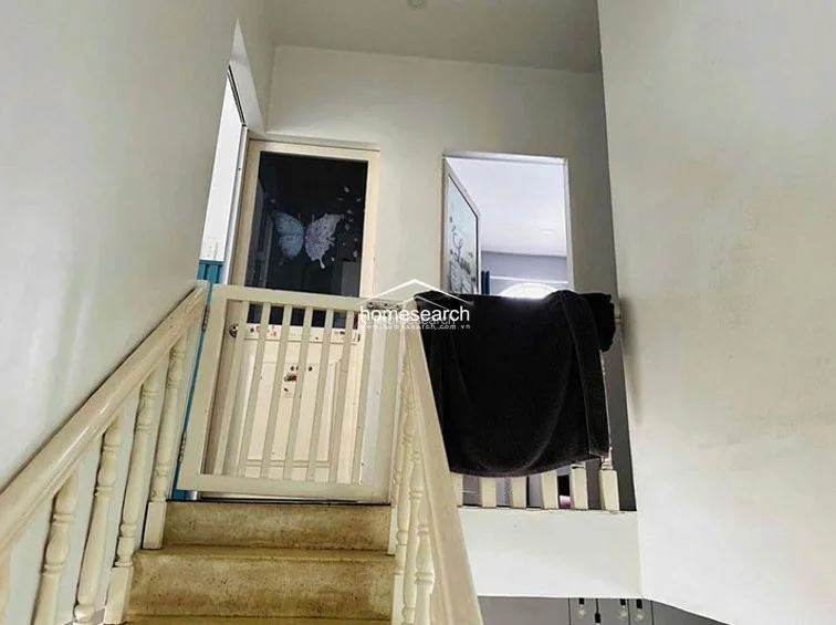 This staircase landing features a wooden safety gate, indicating a family-friendly layout, and leads to multiple upper-level rooms. The space is simple and utilitarian, with white walls and a neutral staircase design that maintains a consistent architectural flow throughout the home.