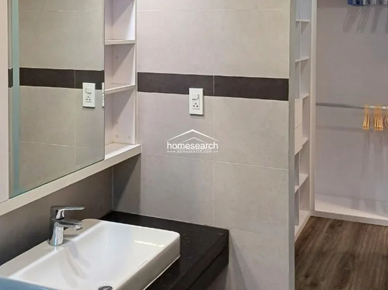 This bathroom area features a sleek vanity with a black countertop, a white basin, and a wall-mounted mirror with integrated shelving. Adjacent to the vanity is an open-concept walk-in closet with white shelving and hanging rods, maximizing storage efficiency in a compact footprint.