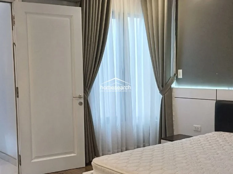 This bedroom highlights a contemporary aesthetic with a dark grey accent wall and a custom-built headboard featuring integrated LED lighting. The room is furnished with a comfortable bed and matching nightstands, maintaining a cohesive and modern interior design.