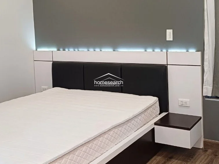 This close-up of the bed area showcases the high-quality craftsmanship of the built-in furniture, including the sleek headboard and floating bedside storage. The neutral color palette and recessed lighting contribute to a serene and modern atmosphere, reflecting excellent maintenance.