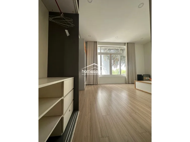 This perspective highlights a minimalist bedroom layout with a low-profile bed frame and integrated cabinetry. The room maintains a bright, airy feel with recessed ceiling lighting and neutral tones, offering a functional and well-maintained living space.